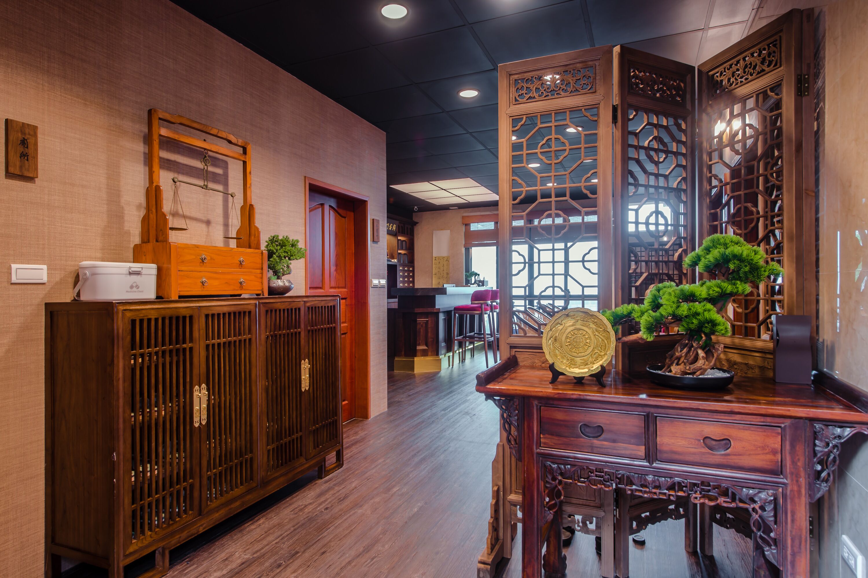 A traditional interior with wooden furniture, a potted plant, and a decorative screen.