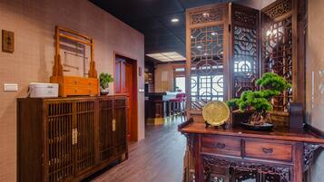 A traditional interior with wooden furniture, a potted plant, and a decorative screen.
