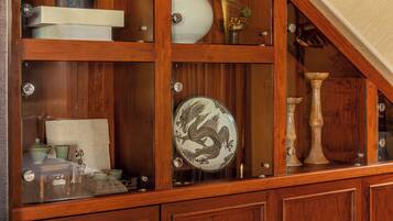 A wooden cabinet with glass doors containing various items like a teapot, a vase, and a decorative plate.