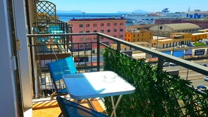 Ein Balkon mit Tisch und Stühlen, mit Blick auf eine Marina mit Booten und Gebäuden.