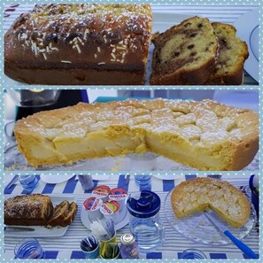 A variety of baked goods including a loaf of bread, a cake, and pastries, displayed on a table with plates and utensils. - Zonaporto (Naples)