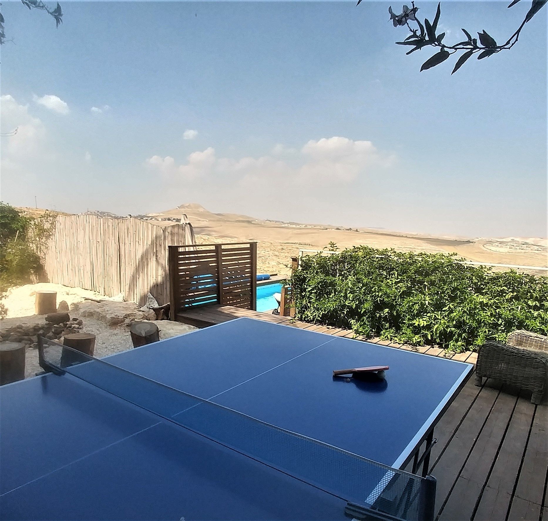 A ping pong table on a wooden deck with a view of a desert landscape.