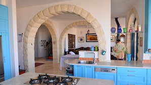 A kitchen with blue cabinets, a gas stove, and a sink. There are stone arches in the background. - Villa Herodion (Tekoa)