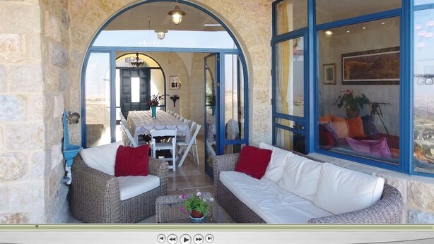 A cozy interior with stone walls, a dining area, and a seating area with wicker furniture and cushions. - Villa Herodion (Tekoa)