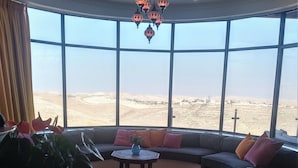 A spacious living room with a large window offering a desert view, a round coffee table, and a modern chandelier. - Villa Herodion (Tekoa)
