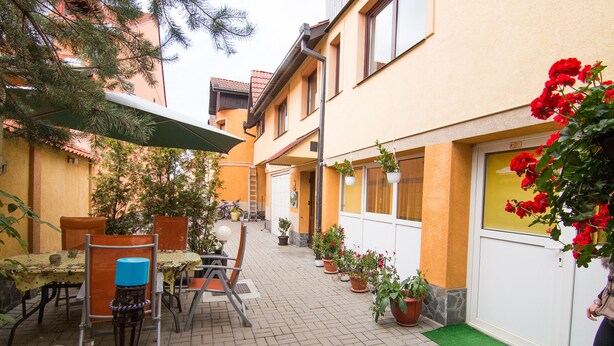 Une cour avec une table et des chaises, des plantes en pot et une porte dotée d’une fenêtre.