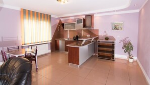 Une cuisine moderne dotée d’un îlot central, un coin repas avec une table et des chaises, et un espace de vie avec un canapé.