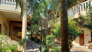 Um pátio com um caminho central, ladeado por edifícios com varandas e plantas em vasos.
