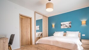 A modern bedroom with a large bed, wooden flooring, a desk with a chair, and a blue accent wall with artwork. - Stunning private villa for 8 people with WIFI, A/C, private pool, TV and terrace (Pazin)