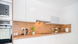 A modern kitchen with white cabinets, a wooden countertop, a built-in oven, a coffee maker, and a potted plant. - Stunning private villa for 8 people with WIFI, A/C, private pool, TV and terrace (Pazin)