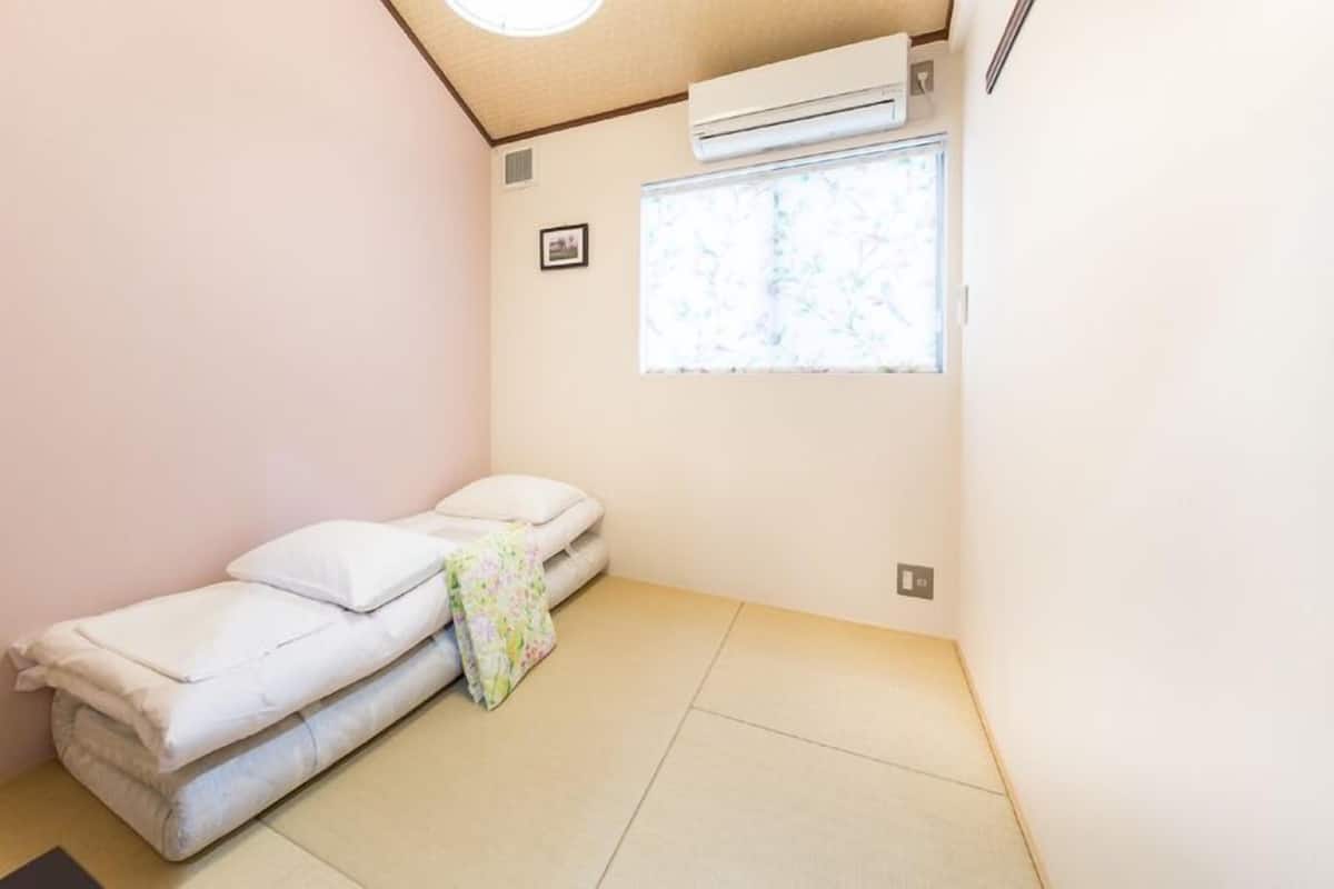 A small room with a single bed, a window with a view, and an air conditioning unit.