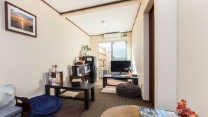 A living room with a sofa, a coffee table, a television, and a bookshelf. - Guesthouse Na-No-Hana - Caters to Women - Hostel (Kyoto)