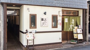 A traditional Japanese building with a wooden entrance, a green curtain, and various signs and menus displayed outside. - Guesthouse Na-No-Hana - Caters to Women - Hostel (Kyoto)