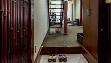 A narrow hallway with a wooden door on the left and a wooden door on the right. There is a small step leading to a landing with a pair of shoes on it.