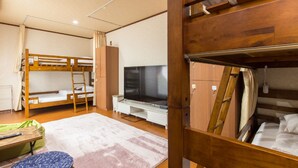 A compact room with bunk beds, a flat-screen TV, a desk, and a small seating area. - Guesthouse Na-No-Hana - Caters to Women - Hostel (Kyoto)