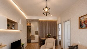 Una sala de estar moderna con una televisión de pantalla plana, una mesa de centro de madera, un sofá color beige y un área de comedor con una mesa y sillas.