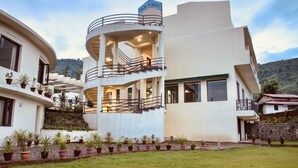 A modern hotel with a curved structure, multiple balconies, and a sign indicating it is a hotel. - The Palm Hotel (Nainital)