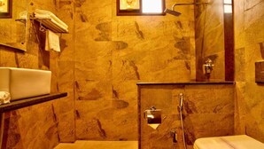 A bathroom with marble walls, a toilet, a sink, and a shower area. - The Palm Hotel (Nainital)