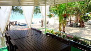 A wooden deck with a view of a beach and palm trees. - Tharadol Beach Resort (Tha Sala)