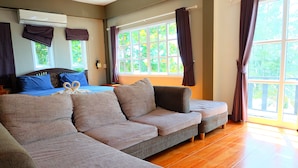 A modern room with a large window, a sofa, a bed, and an air conditioning unit. - Tharadol Beach Resort (Tha Sala)