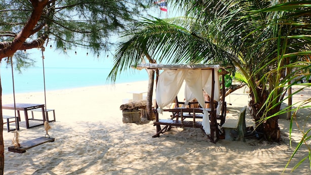 A beach setting with a wooden swing, a small covered seating area, and a bench. - Tharadol Beach Resort (Tha Sala)
