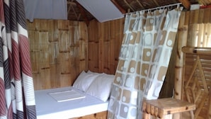 Una habitación de madera con una cama, una pared de bambú y una escalera de madera.