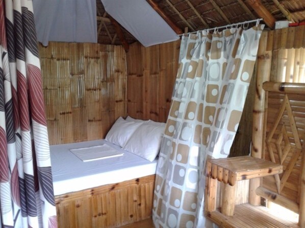 A wooden room with a bed, a bamboo wall, and a wooden ladder. - Coco Garden Villas (El Nido)