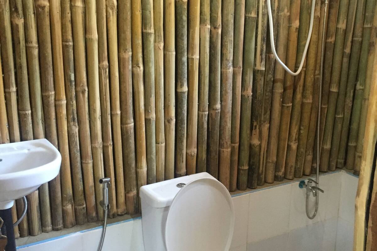 Casa de banho com sanita, lavatório e chuveiro.