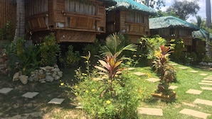 Un resort con edificios de madera, techos de paja y un jardín con plantas tropicales.