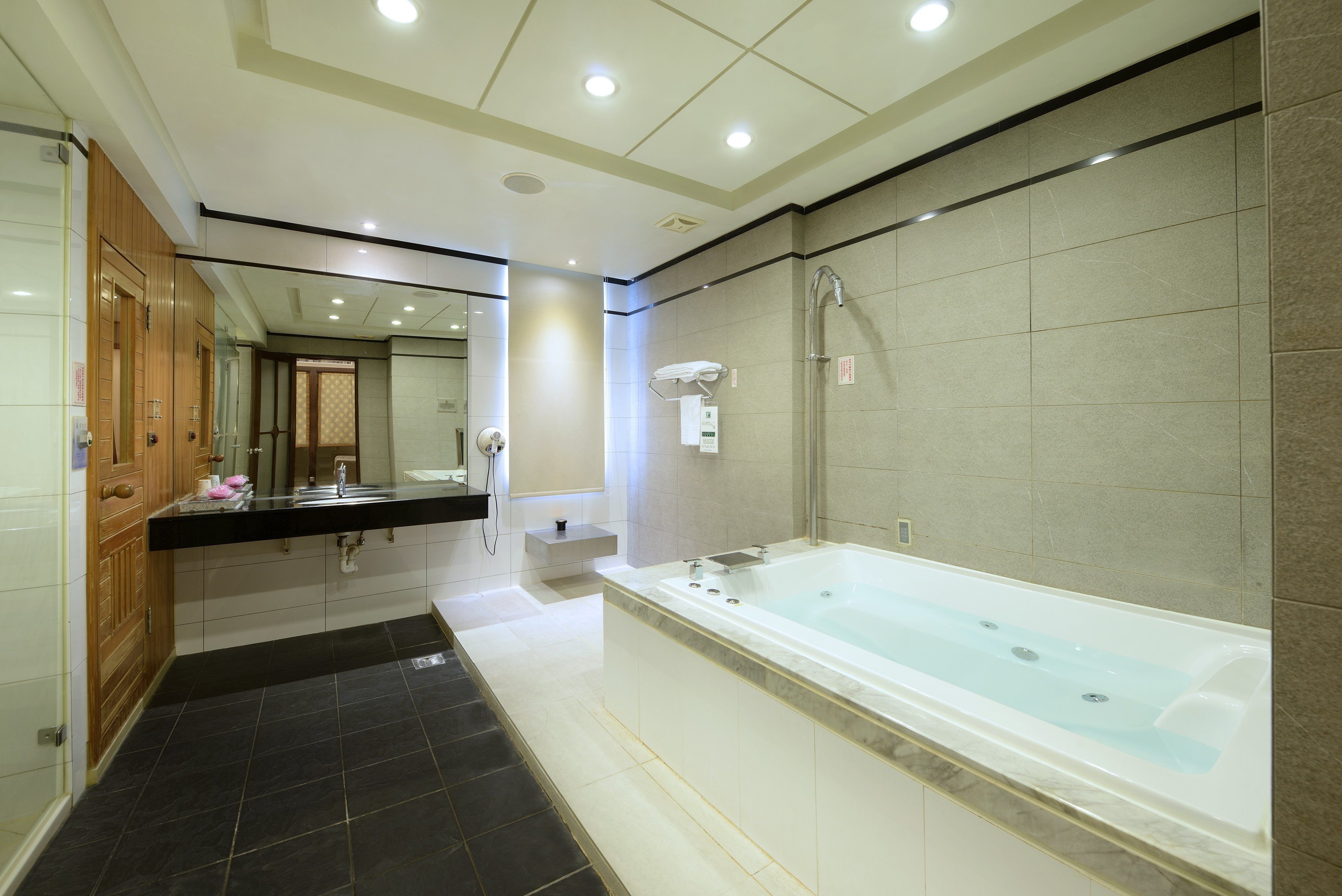 Un baño moderno con una bañera grande, un tocador de madera y un espejo.