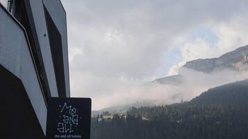 A mountainous landscape with a forested valley and a building with a sign reading "me and all hotels".