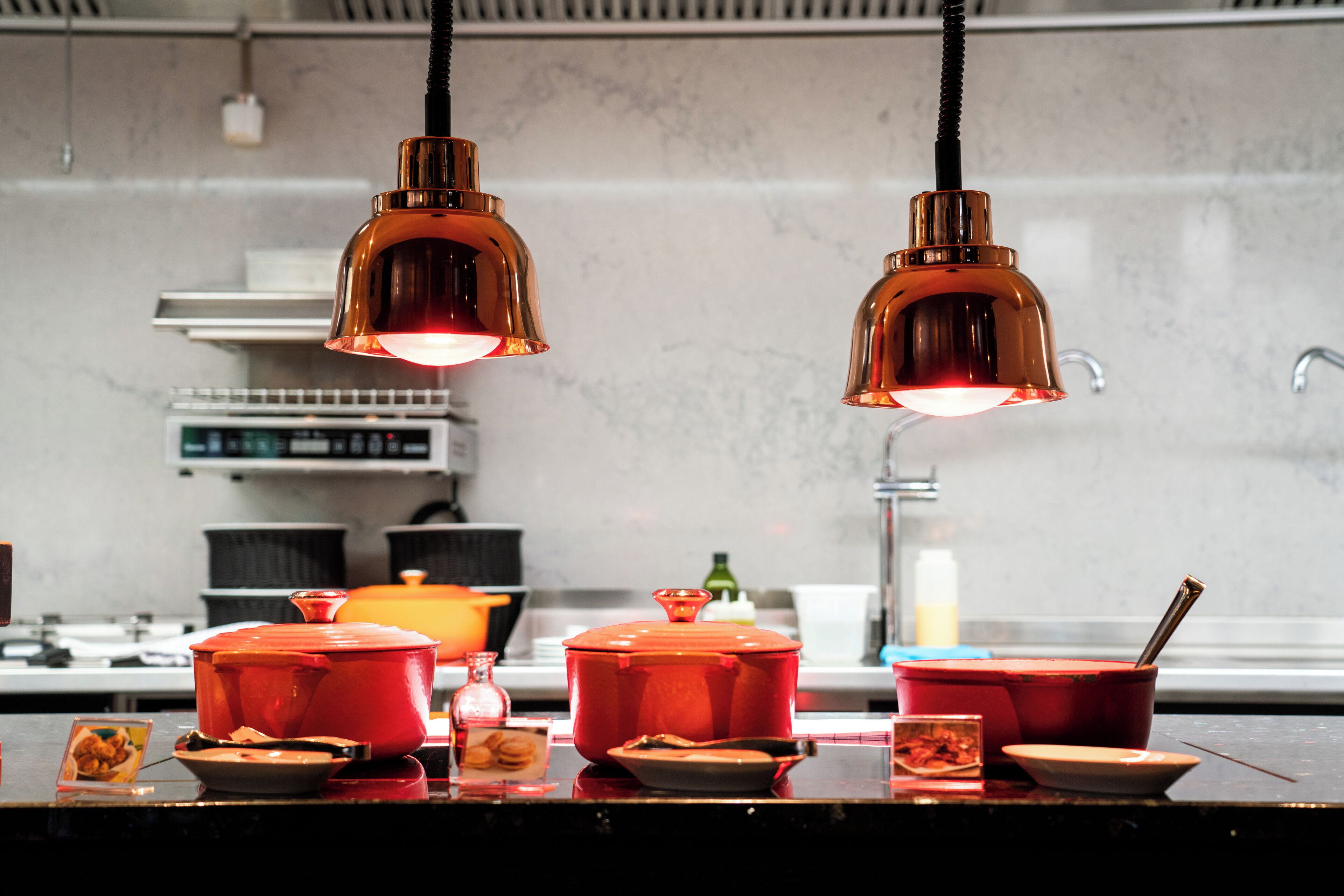 Una cocina con dos lámparas colgantes, una estufa y varios utensilios sobre la encimera.