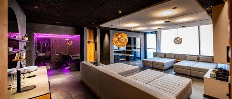 Una habitación de hotel moderna con una amplia zona de estar, un separador de vidrio y un diseño de techo único.