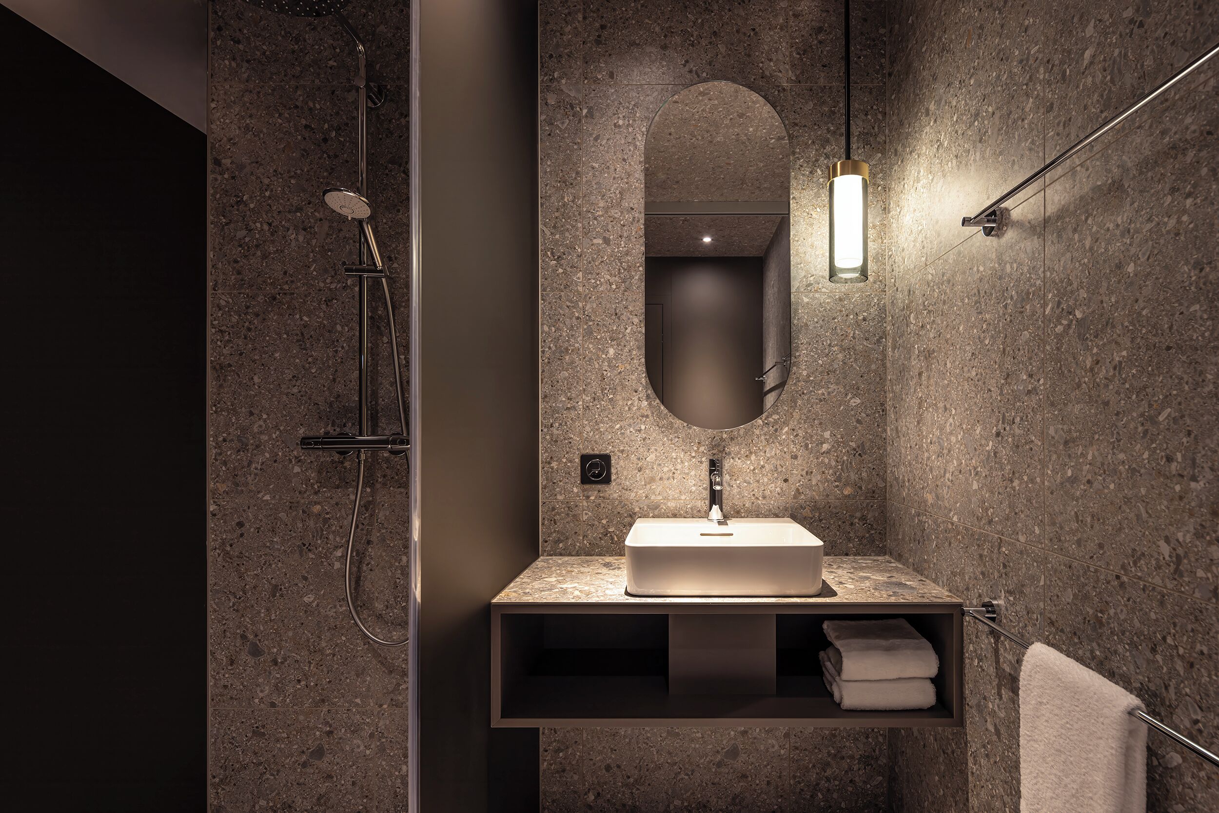 A modern bathroom with a granite countertop, a rectangular sink, a wall-mounted mirror, and a towel rack.