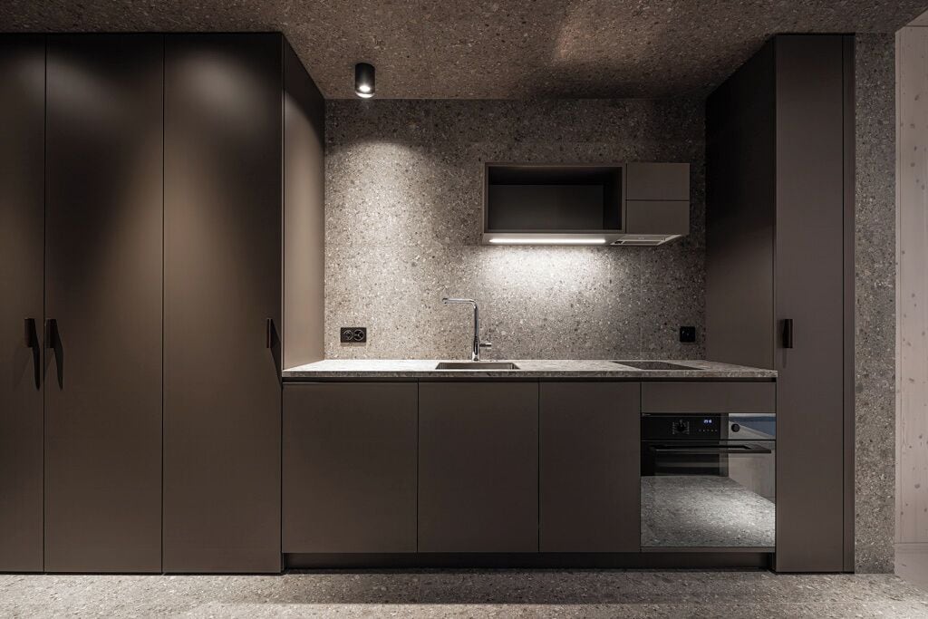 A modern kitchen with dark cabinetry, a built-in oven, and a countertop.