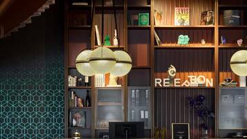 A reception area with a dark wood reception desk, a geometric patterned wall, and a 'RECEPTION' sign.