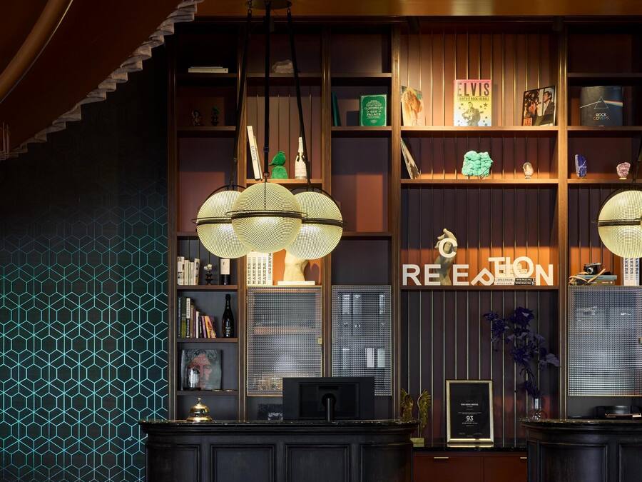 A reception area with a dark wood reception desk, a geometric patterned wall, and a 'RECEPTION' sign.
