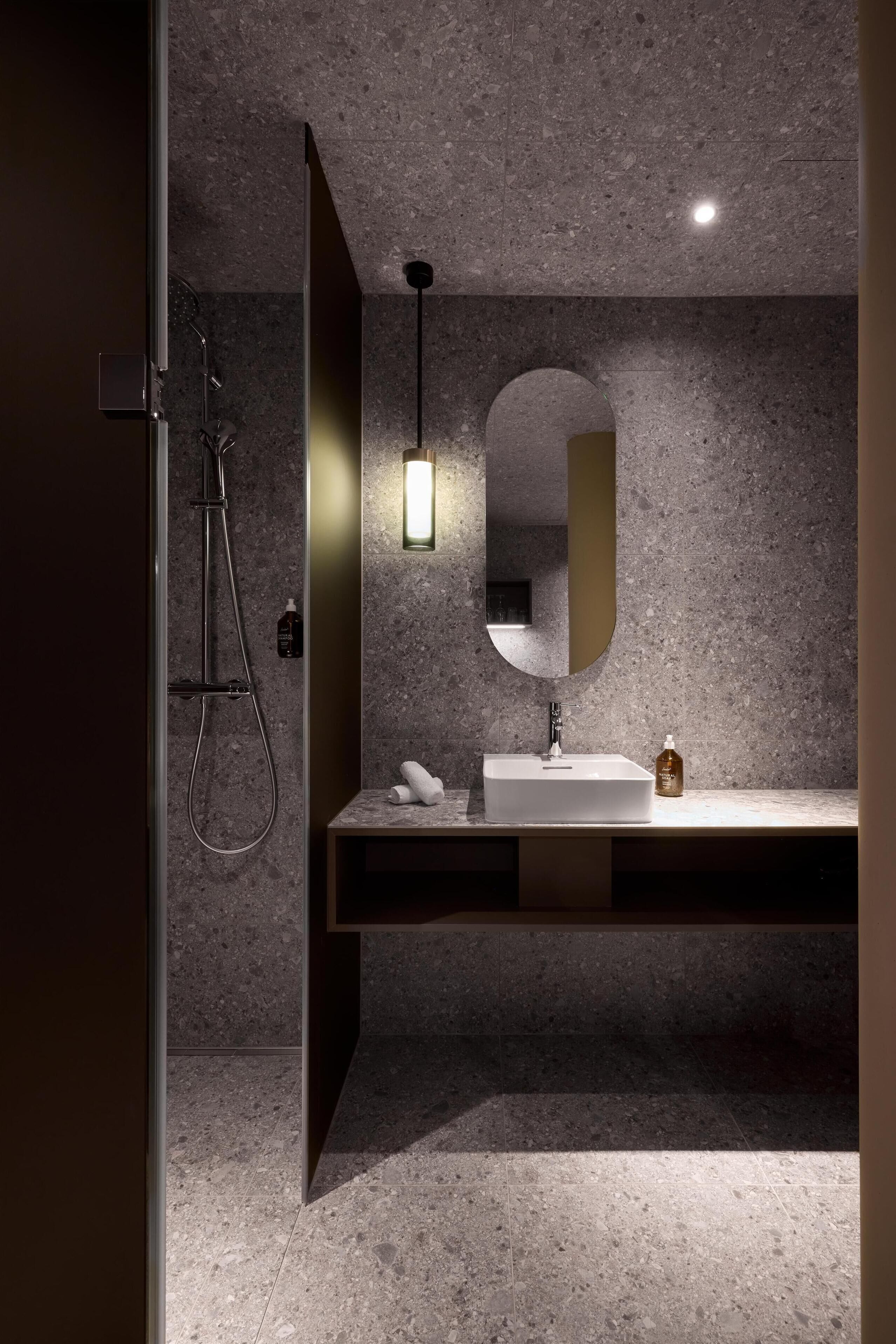 Un baño moderno con ducha, lavamanos y espejo.