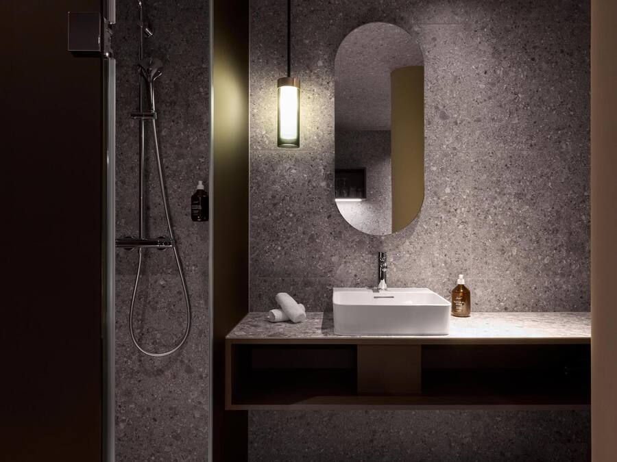 Un baño moderno con ducha, lavamanos y espejo.