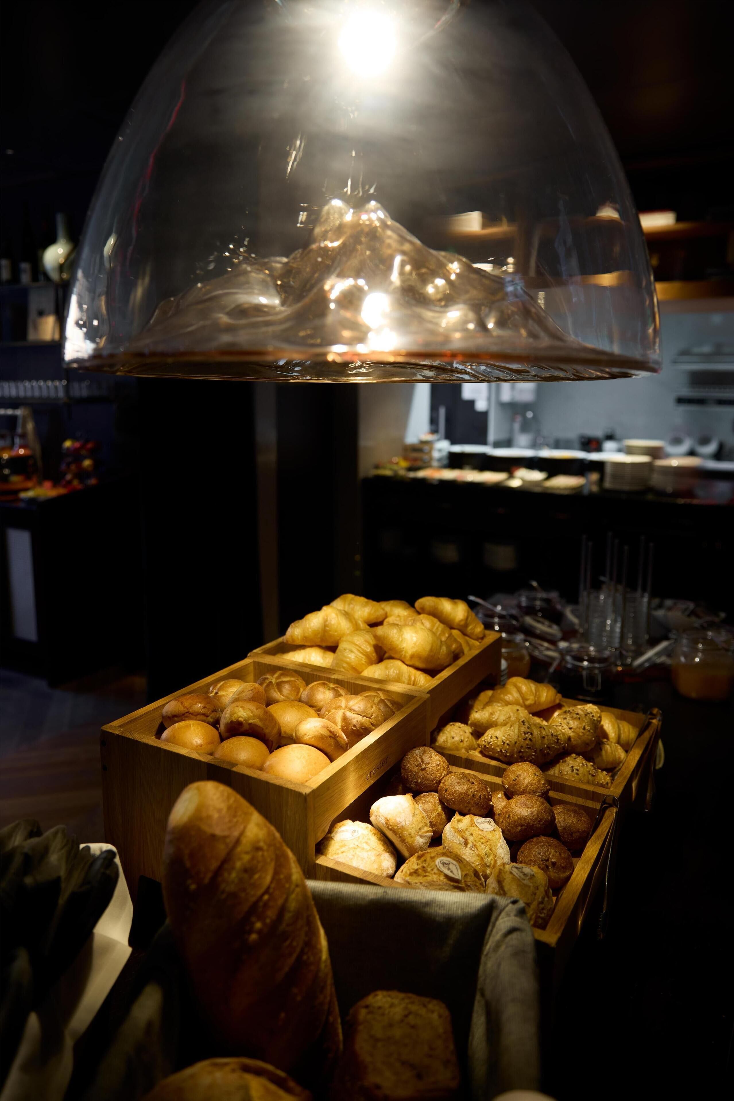 Una vitrina de panadería con diversos productos horneados bajo una campana de cristal.