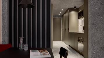 A modern dining area with a dark table, a single chair, a pendant light, and a magazine.