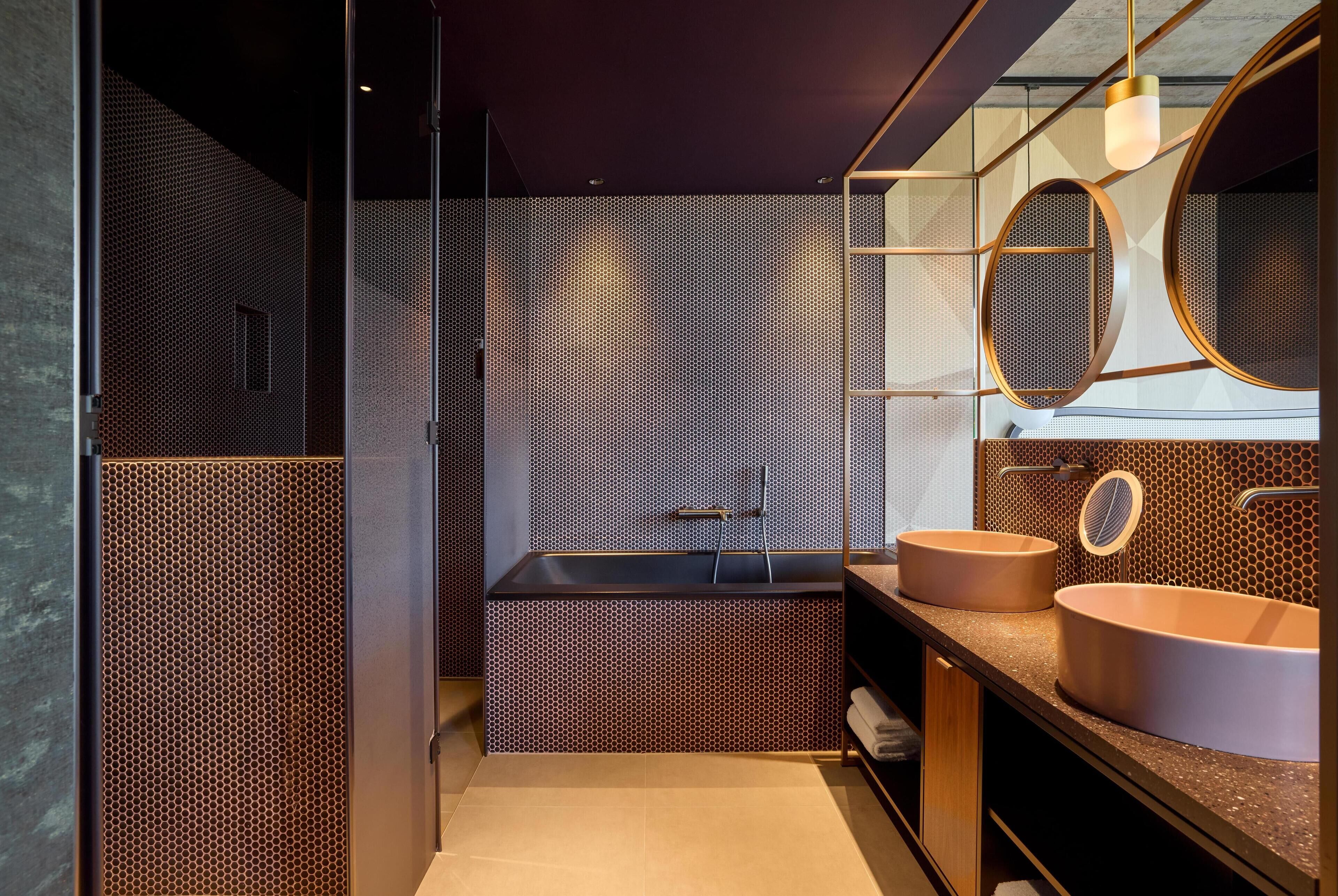 A modern bathroom with a large bathtub, two sinks, and a mirror.