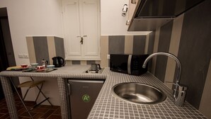 A compact kitchen with a sink, a microwave, and a small table with a kettle. - Fori Romani B&B (Rome)