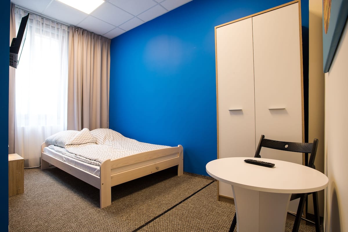 Ein Zimmer mit einem Bett, einem Sessel, einem kleinen Tisch und einem Schrank.