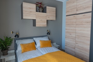 A bedroom with a bed, bedside tables, a wall-mounted cabinet, and a potted plant. -  Moon Hostel Poznań (Poznan)