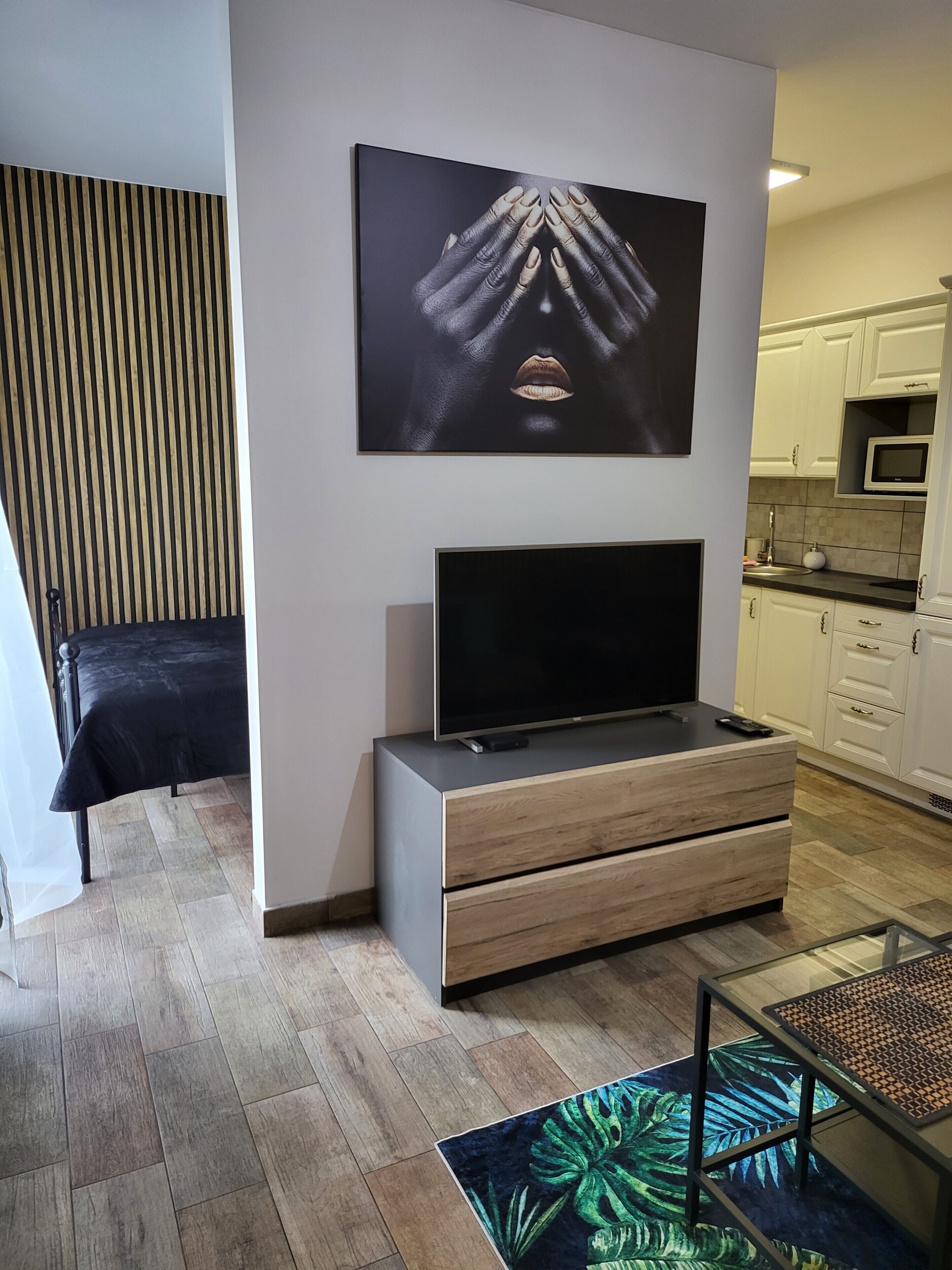 A modern living room with a flat-screen TV, a sofa, a coffee table, and a decorative wall piece.