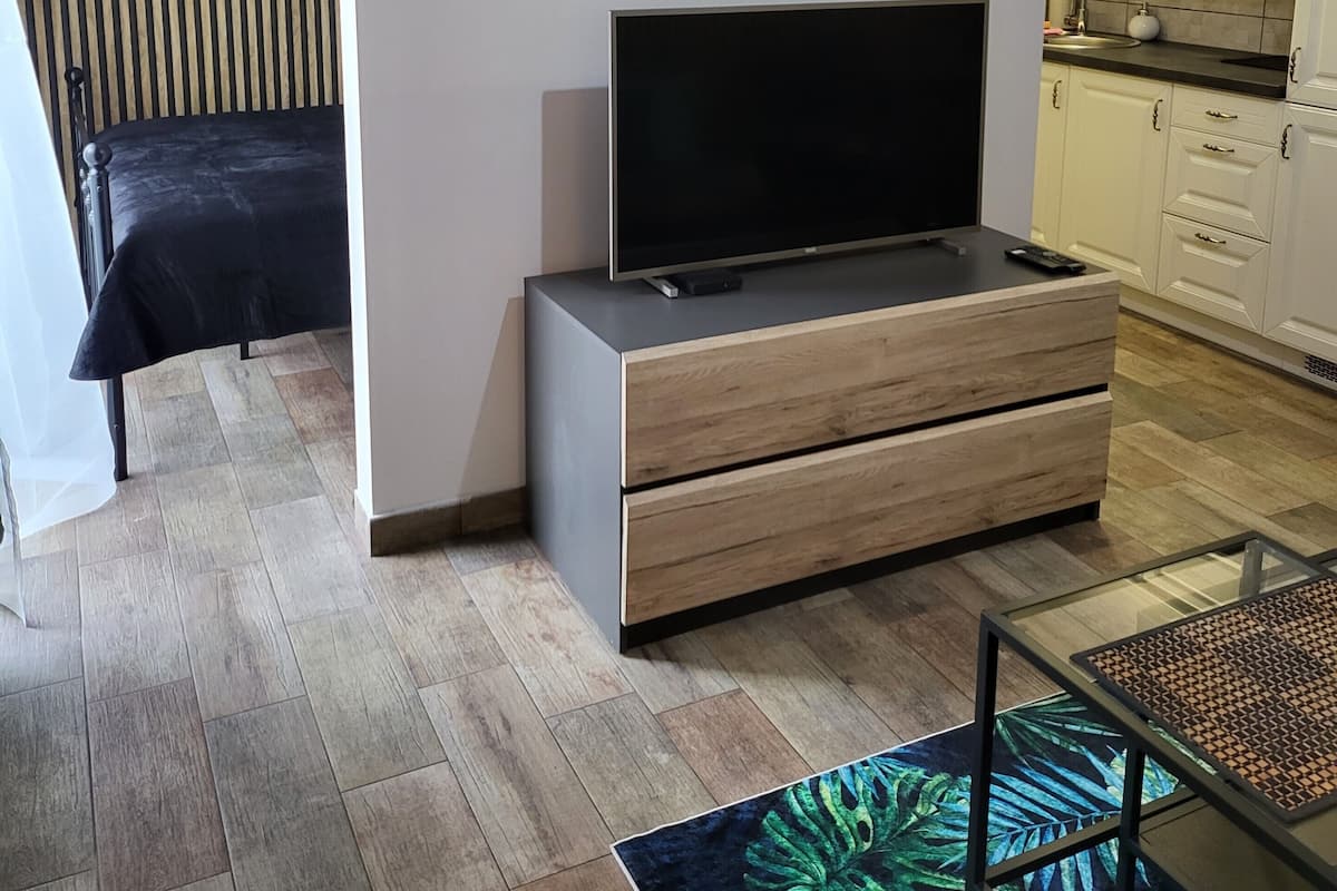 Ein modernes Wohnzimmer mit Flachbildfernseher, einer Couch, einem Couchtisch und einem Wandbild.