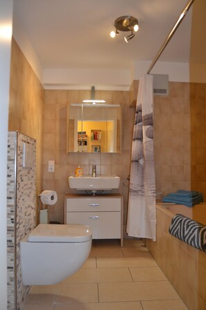 A bathroom with a toilet, sink, mirror, and shower curtain. - Ferienwohnung Schelsen (Moenchengladbach)