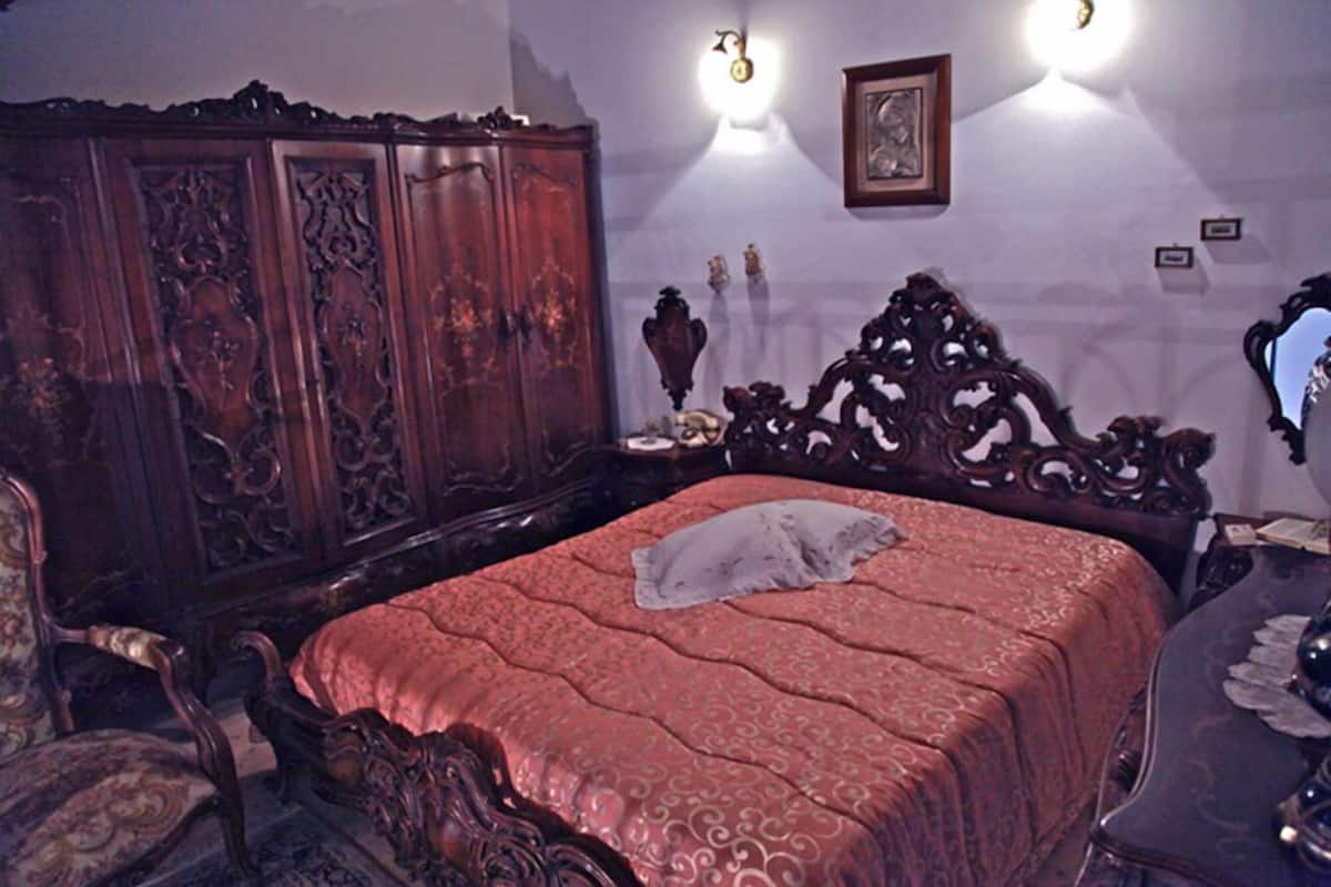 A bedroom with a large wooden bed, a matching wardrobe, and ornate furniture.