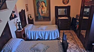 A bedroom with two beds, a dresser, a mirror, and a painting on the wall.